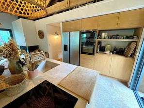 Una cocina moderna con una isla central, electrodomésticos integrados y varios armarios de almacenaje.