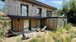 Una casa moderna de madera con balcón, mobiliario exterior y jardín.