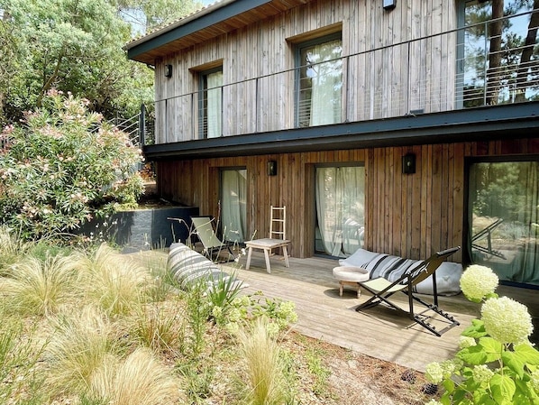 Una casa moderna de madera con una terraza, asientos exteriores y una escalera.
