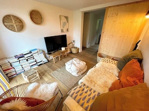 Una sala de estar con televisor, estanterías, sofá y una alfombra estampada.
