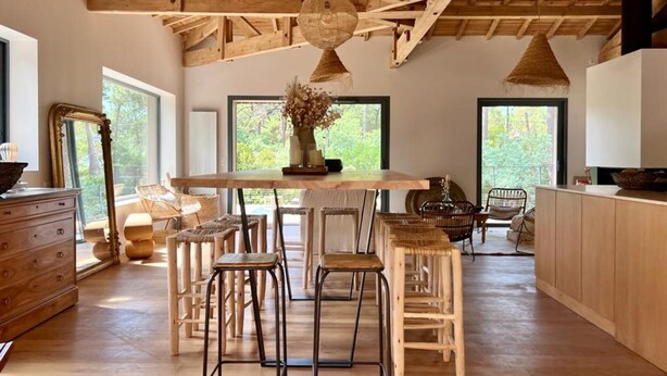 Una cocina amplia con vigas de madera, una isla central y varios taburetes de bar.