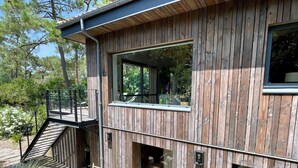 Una casa moderna de madera con terraza, escaleras y grandes ventanales.