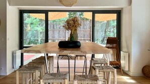 Un comedor amplio con una mesa y sillas de madera, ventanas grandes y un techo alto con vigas a la vista.