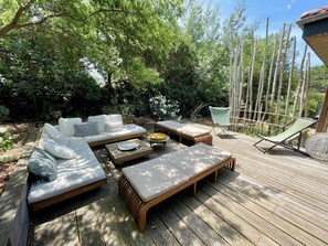 Een terras buiten met een loungeset, een comfortabele stoel en een bijzettafeltje.