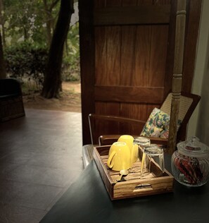 A wooden table with a tray containing yellow mugs, salt and pepper shakers, a spoon, and a glass jar with a lid. - Dancing Dugong (Port Blair)