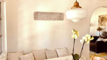 A living room with a white sofa, a table with a vase of flowers, and a wall-mounted sign.