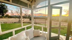 A room with a bed, large windows, and a view of a grassy field and trees. - Anavo Farm House ~ a storybook stay with Animals (Solvang)