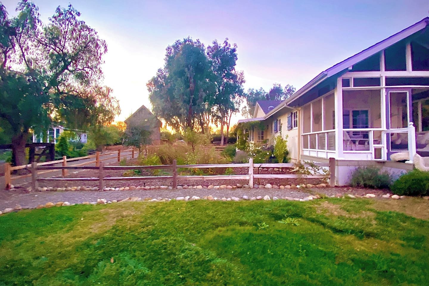 A residential property with a fenced yard, a wooden deck, and a house with large windows.