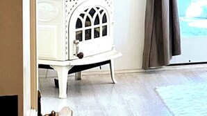 A room with a white cabinet with a decorative top, a wooden floor, and a view through a glass door. - Anavo Farm House ~ a storybook stay with Animals (Solvang)