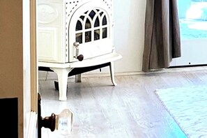 Une pièce avec un meuble blanc orné d’un élément décoratif sur le dessus, un plancher en bois et une vue à travers une porte vitrée.