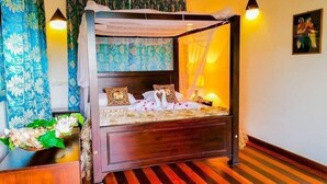 A four-poster bed with a canopy, floral-patterned curtains, and a painting on the wall. - Mass Eco Cabana Yoga & Spa - Unawatuna (Unawatuna)