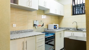 Una cocina con armarios blancos, un microondas, una estufa a gas y un lavamanos.