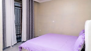 Una habitación con una cama, una puerta con cortinas y una pared lisa.