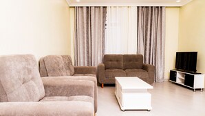Una sala de estar con dos sofás, una mesa de centro y un mueble para televisión.