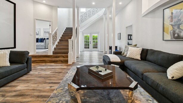 Ein geräumiger Wohnbereich mit einem dunkelgrauen Sofa, einem Couchtisch und einer Treppe, die zu einer zweiten Etage führt.