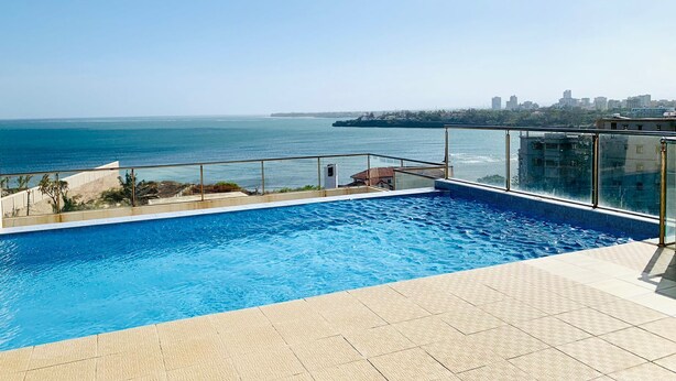 A rooftop swimming pool with a clear view of the ocean and city skyline. - Lux Suites Palm Terraces Apartments  (Mombasa)