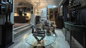 Un interior bien iluminado con una mesa de centro de vidrio, una estatua y un cuadro en la pared.