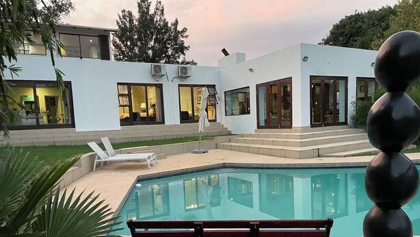 Una casa moderna con piscina, banco y una escultura.