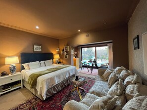A hotel room with a bed, bedside tables, a desk, a chair, and a view of the outdoors.