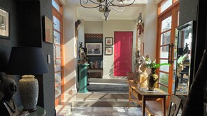 Un pasillo bien iluminado con una puerta roja, una escalera y un comedor con mesa y sillas.