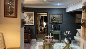 Una sala de estar con un sofá, una mesa de centro, una chimenea y obras de arte en las paredes.