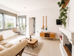 A modern living room with a sofa, a coffee table, a fireplace, and a TV mounted on the wall.