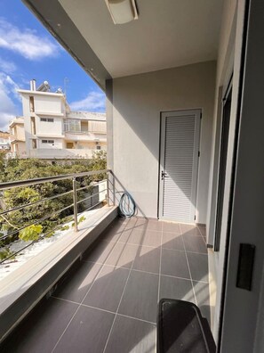 A balcony with a metal railing, a door, and a hose coiled on the floor.