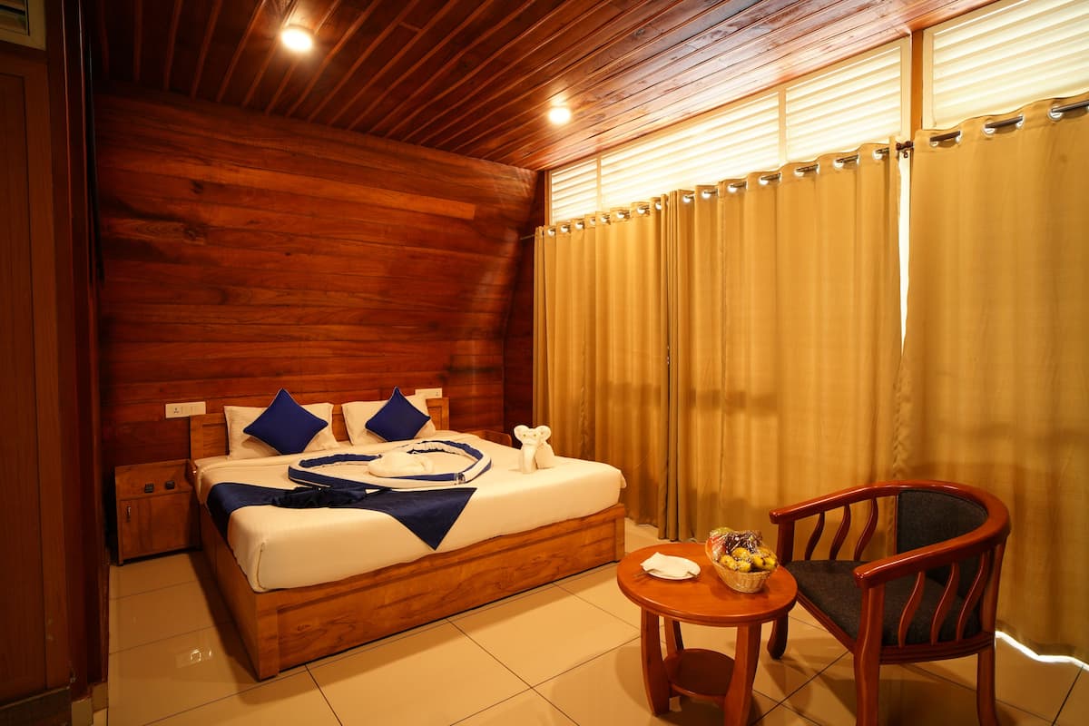 A wooden-paneled room with a bed, a small table with a basket of fruit, and a chair.