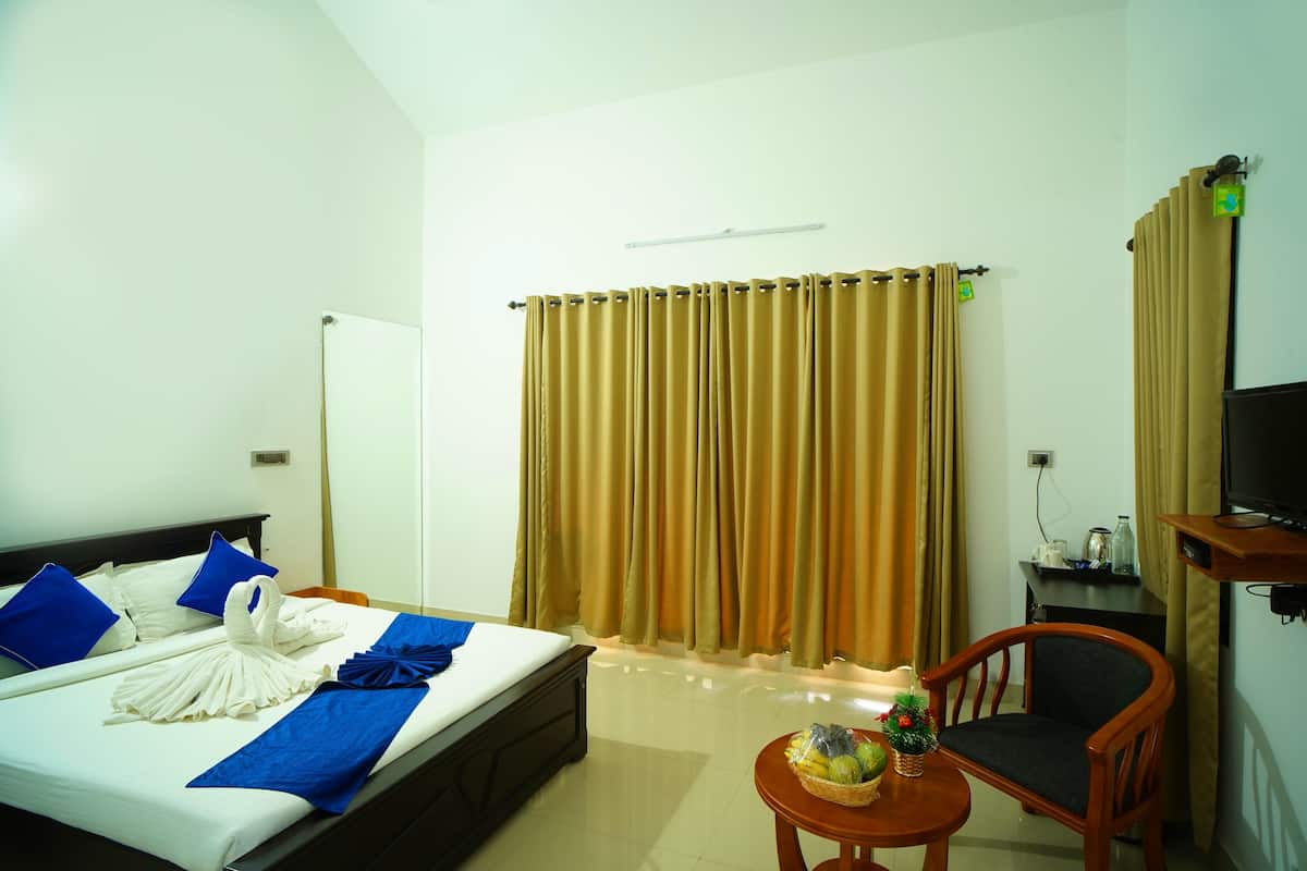 A hotel room with a bed, a chair, a small table with a basket, a television, and curtains.