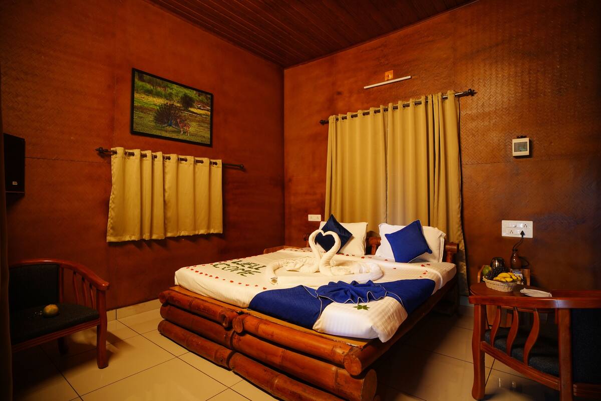 A room with a bed, a chair, a small table, and a painting on the wall.