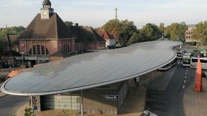 A modern train station with a curved roof, a clock tower, and a sign for 'Herne Bf'. - estrella24 LIVING ROOMS Venice (Herne)