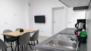 A modern kitchen with a built-in sink, a coffee maker, and a small plant on the dining table. - estrella24 LIVING ROOMS Venice (Herne)