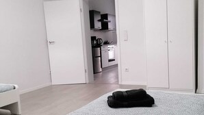 A bedroom with a bed, a wardrobe, and a view into the kitchen. - estrella24 LIVING ROOMS Venice (Herne)