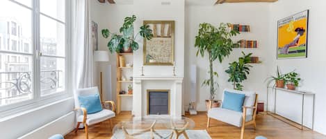 Una sala de estar moderna con chimenea, vigas de madera y un ventanal grande.