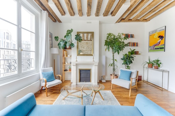 Un salon moderne avec une cheminée, des poutres en bois et une grande fenêtre.