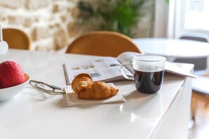 A breakfast setting with a croissant, a glass of coffee, and a bowl of fruit on a table. - in the heart of Paris, premium, with beautiful plants and A/C (Paris)