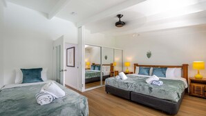 Een hotelkamer met twee bedden, een grote spiegel, houten vloeren en een plafondventilator.