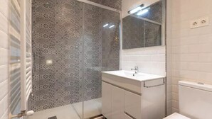 Un bagno moderno con porte doccia in vetro decorato, un lavandino bianco e un water.