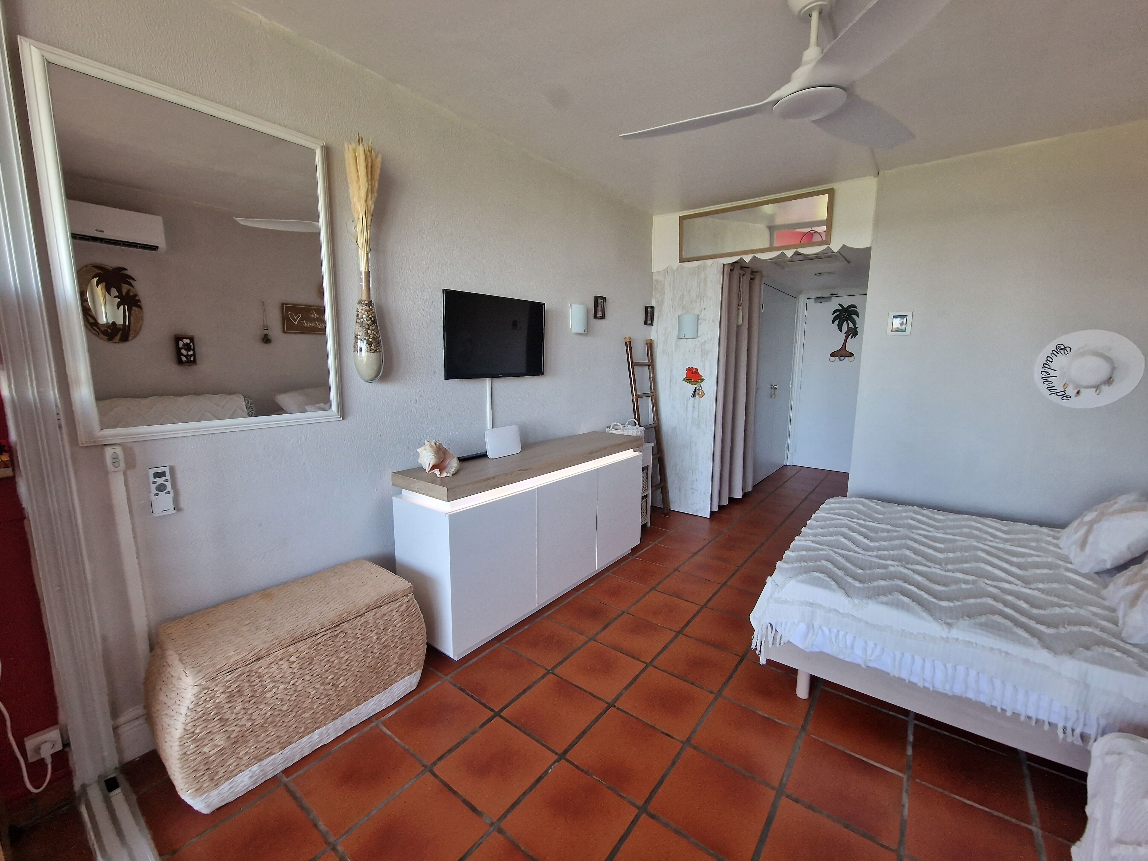 Quarto com cama, mesa de cabeceira, televisão e guarda-roupa.