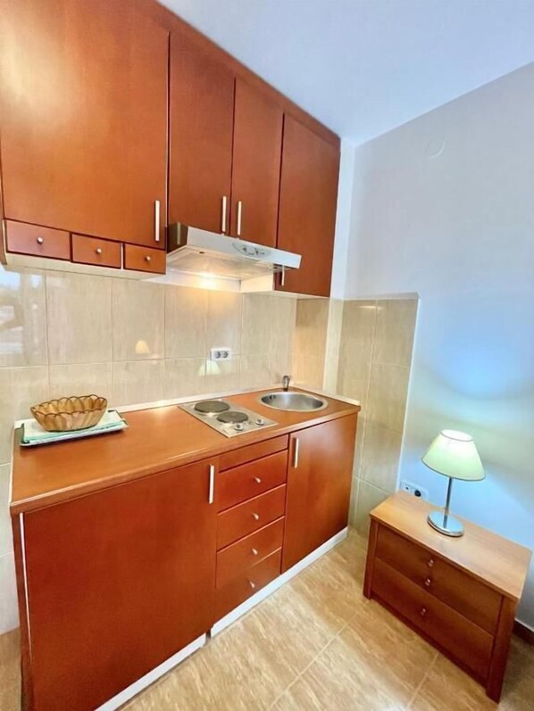 A compact kitchen with wooden cabinets, a built-in stove, and a small countertop. - Apartments Boreta Becici (Becici)