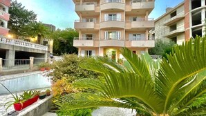 A multi-story residential building with balconies, a courtyard with potted plants, and a clear sky. - Apartments Boreta Becici (Becici)