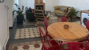 A cozy living room with a round wooden table, red chairs, a sofa, and a washing machine. - « Maison Magnolia » Près de la Gare (Chasse-sur-Rhône)