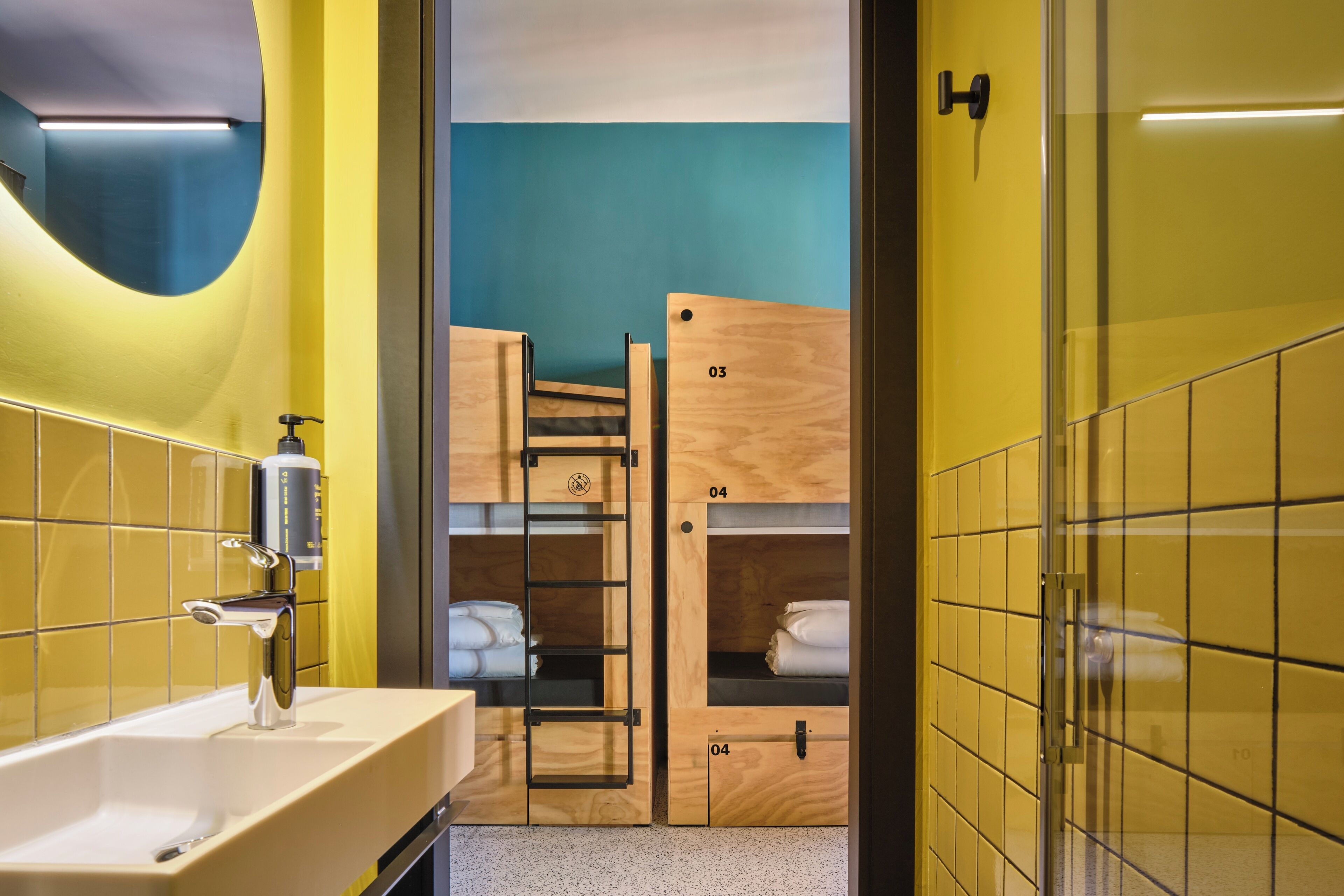A bathroom with a sink, mirror, and wooden bunk beds.