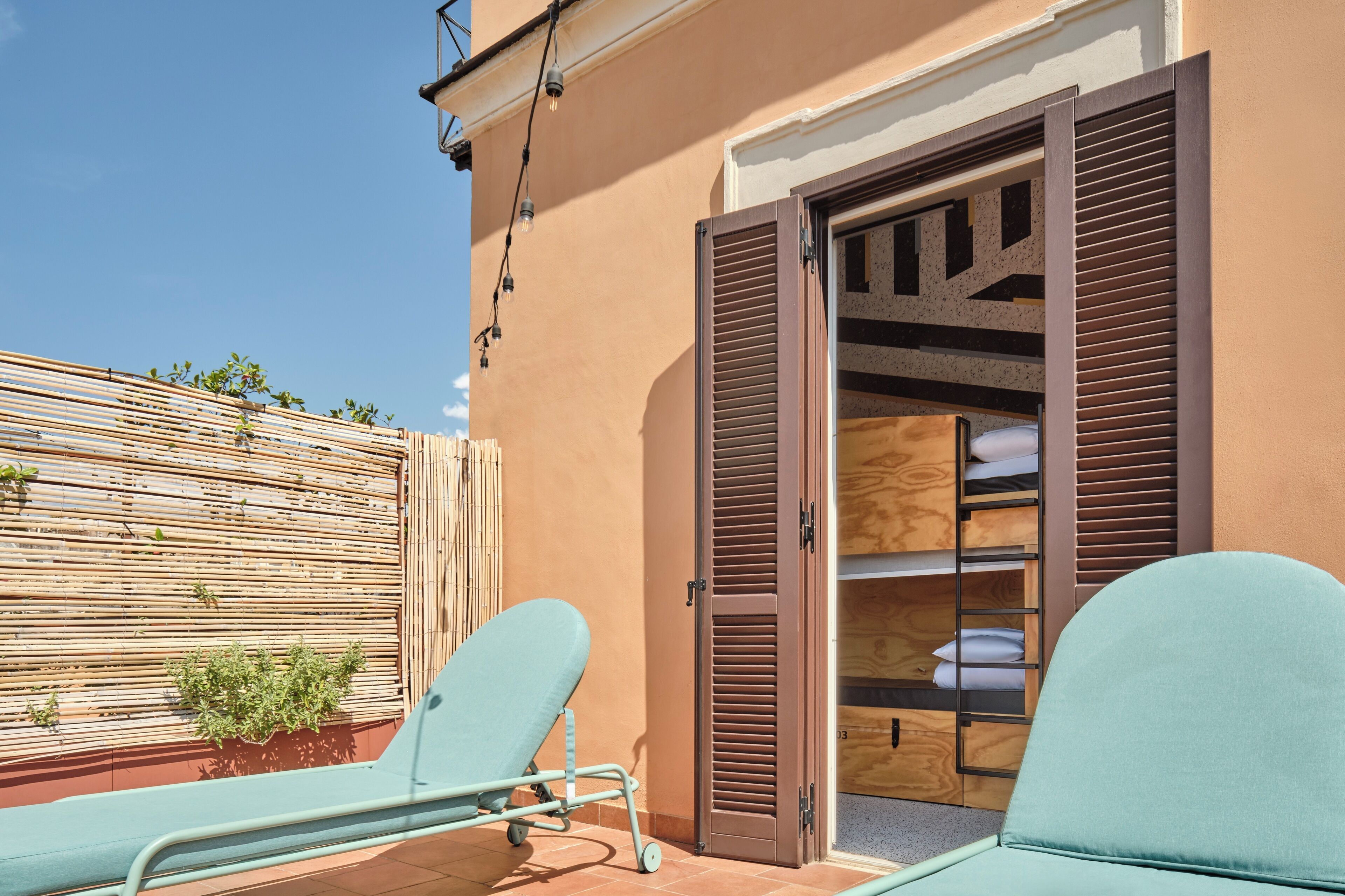 Un balcon avec deux chaises bleu clair, une clôture en bois et une armoire en bois dotée de volets bruns.