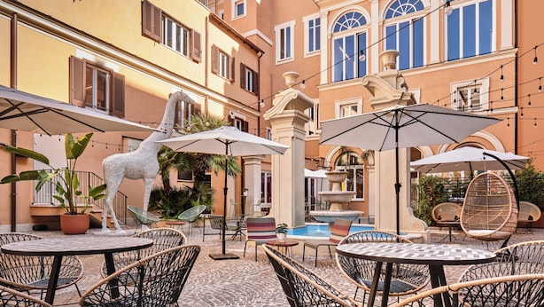 An outdoor patio with wicker furniture, a decorative giraffe statue, and a fountain.