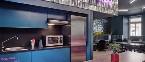 A modern kitchen with a neon sign, a sink, and a microwave.