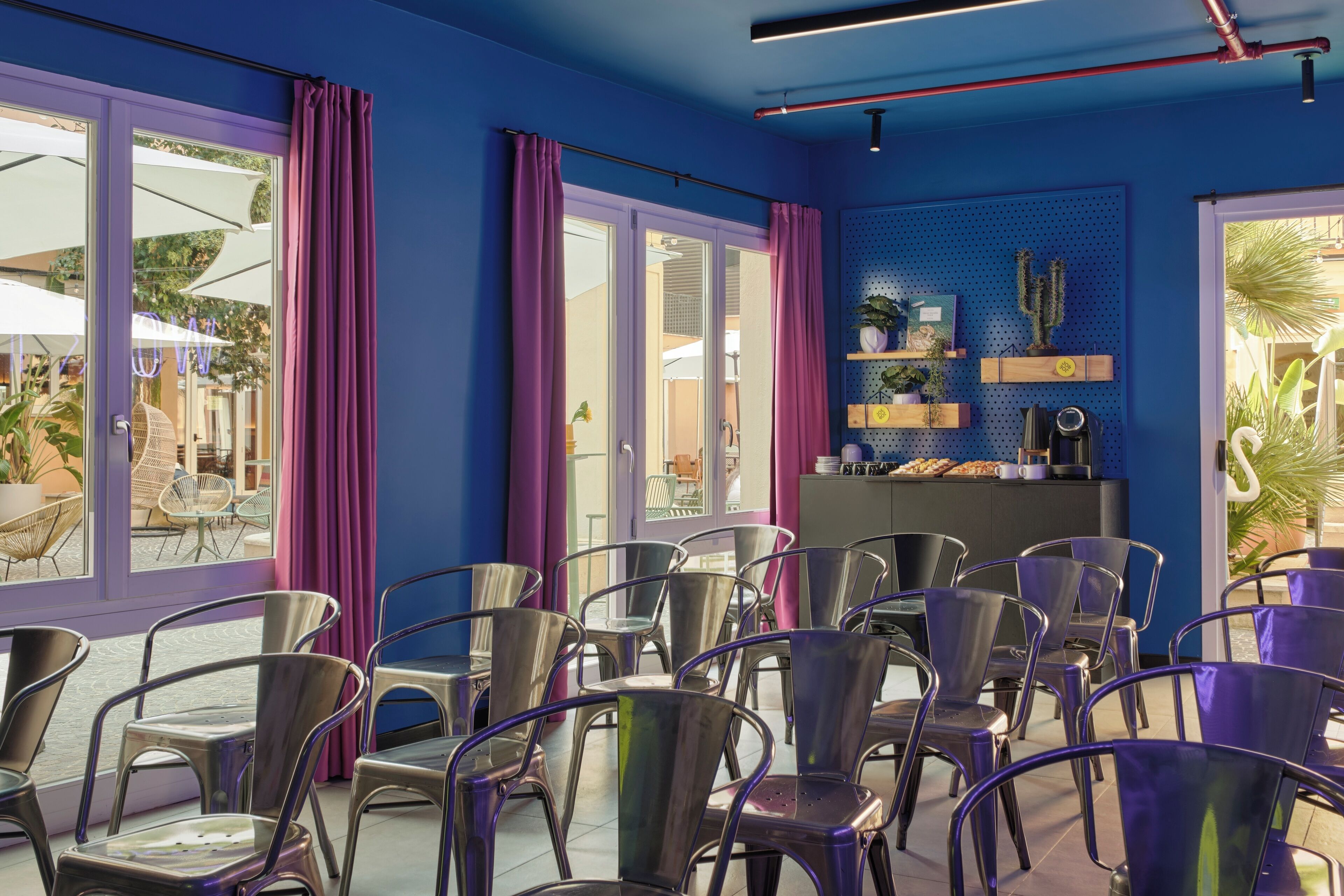 A room with purple walls, metal chairs, and a blue ceiling.