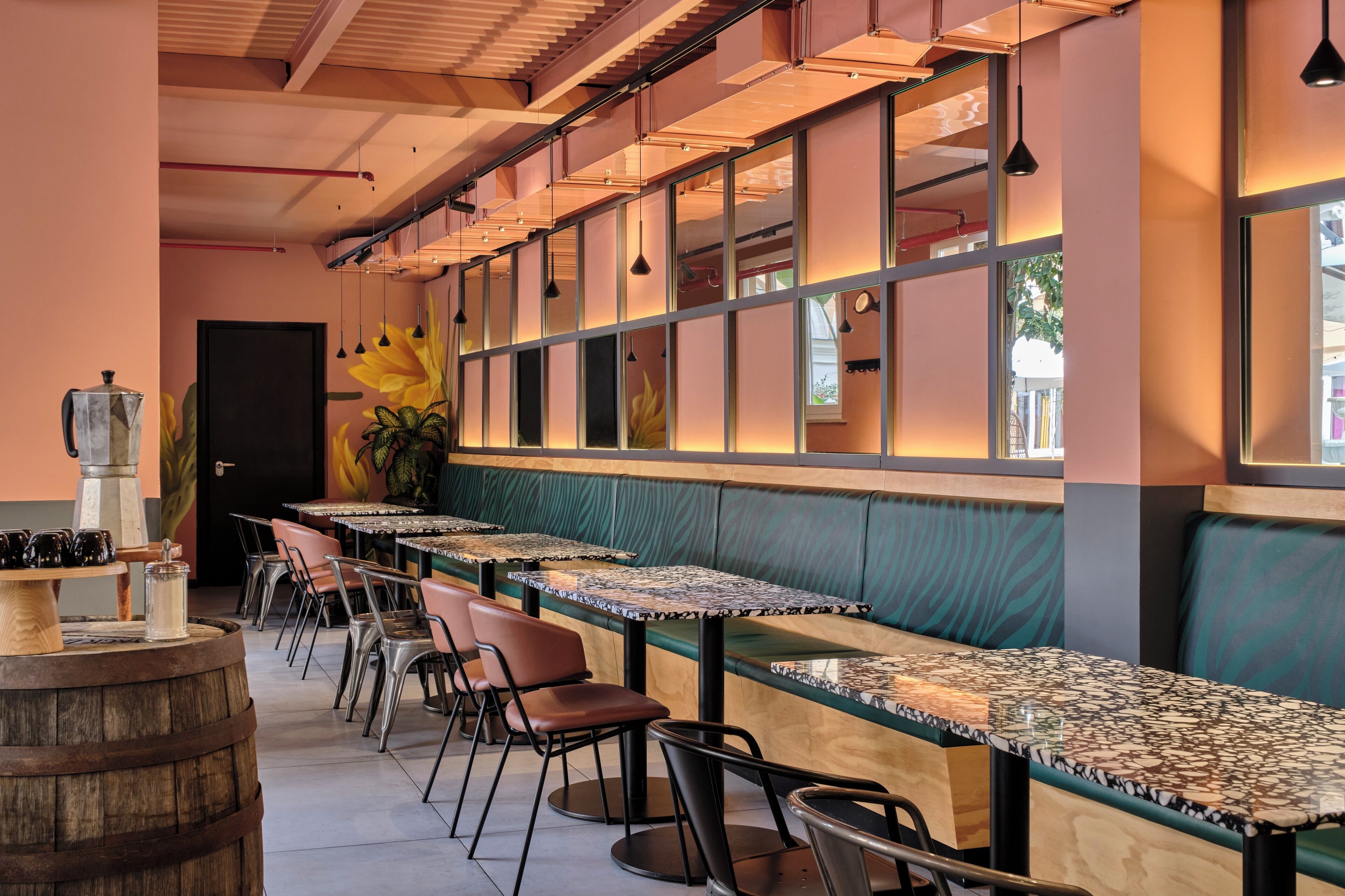 A restaurant with long tables, chairs, and a bar area with a wooden barrel.