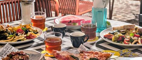 A table set with various dishes, drinks, and a newspaper.