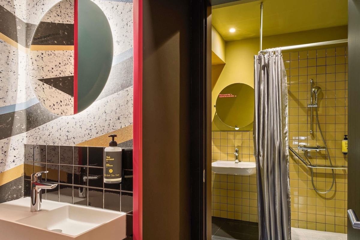 A bathroom with a white sink, a mirror, and a shower with a curtain.